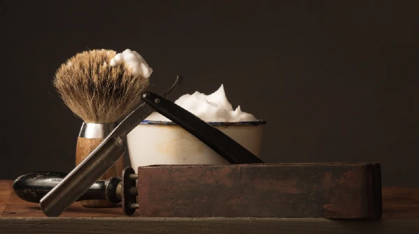 Image d'un coupe-choux, d'un blaireau de rasage, d'un bol à raser et d'un cuir d'affûtage.